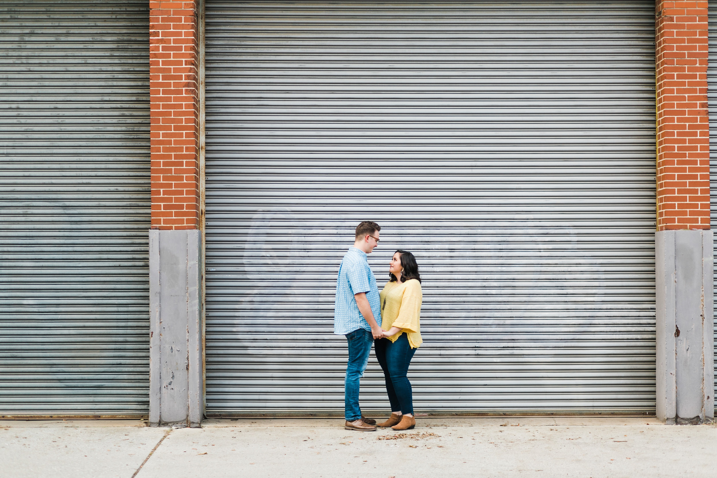 couple standing in front of bay doors engagement session
