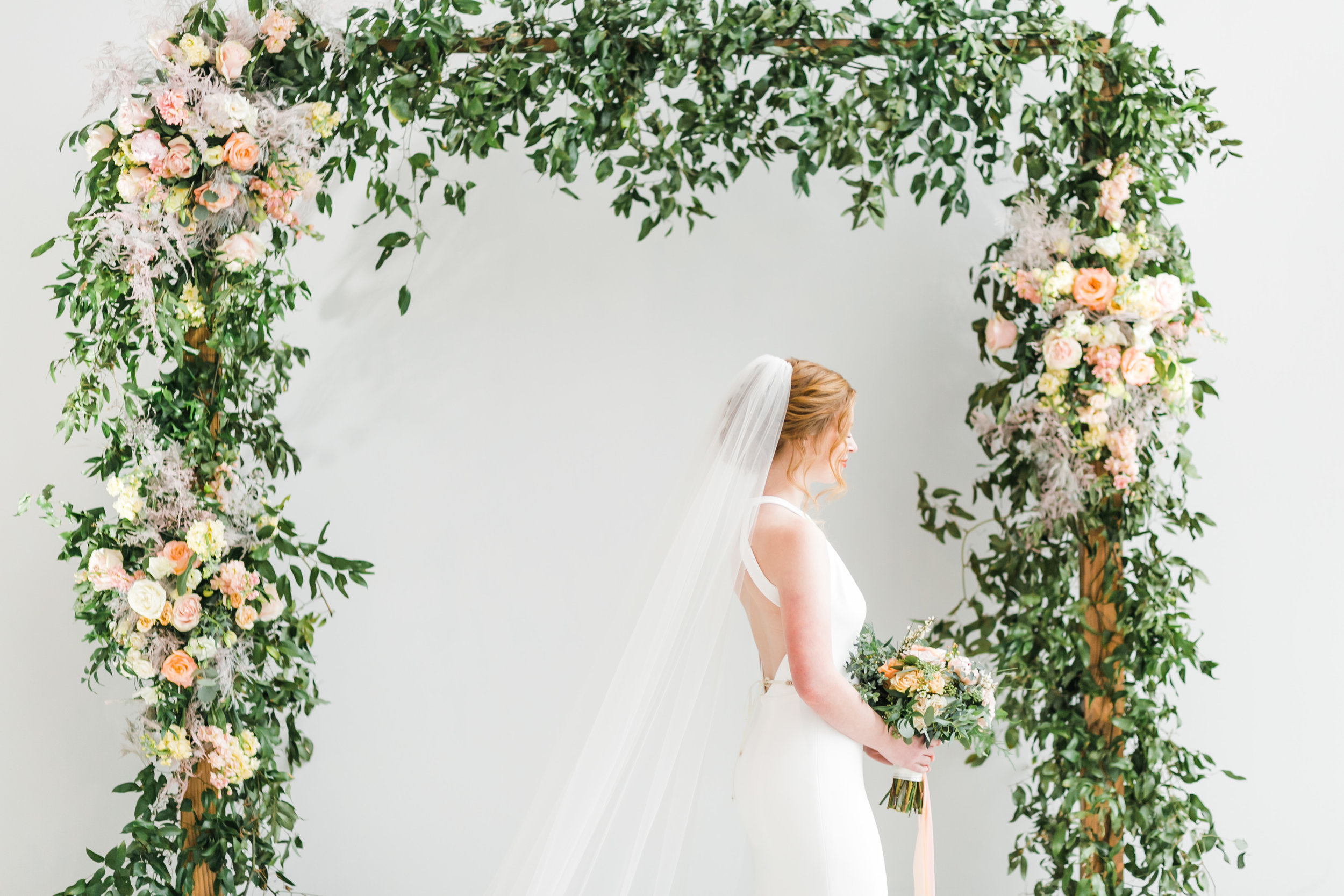 red head bride with veil under spring floral arch indoor at knoxville museum of art
