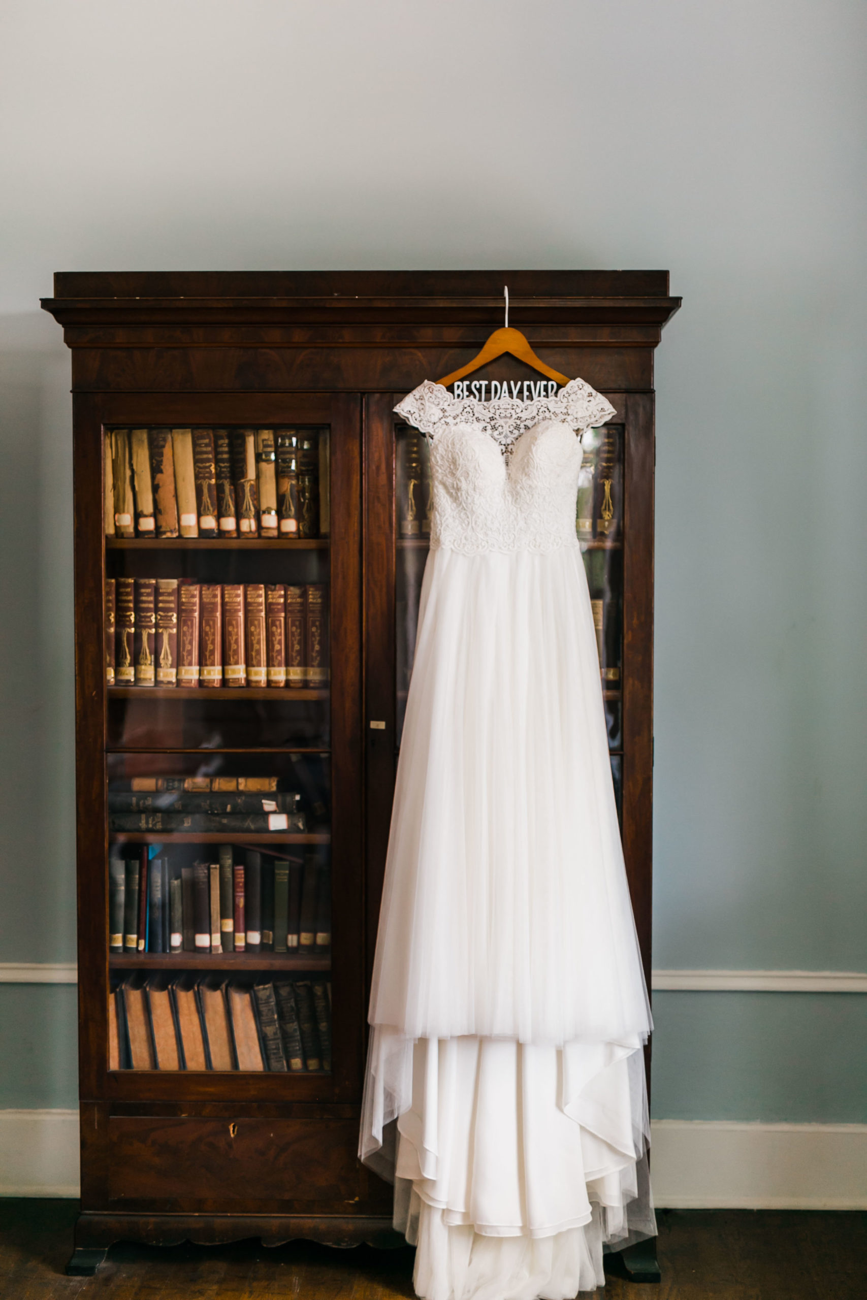flowy wedding dress on best day ever hanger hanging on bookcase in historic bleak house
