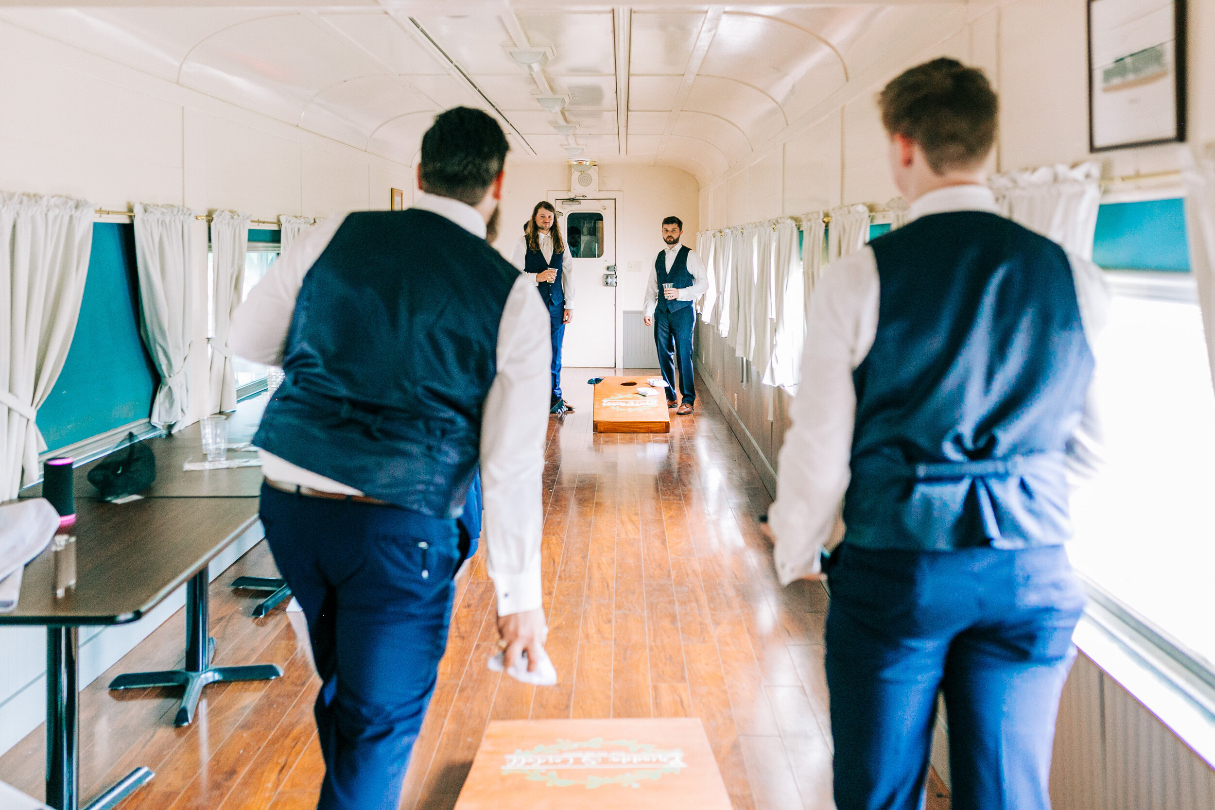 groomsmen playing corn hole at the souther railway station train car